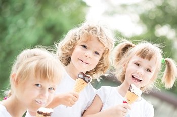 Happy smiling children eating ice-cream outdoors in spring park