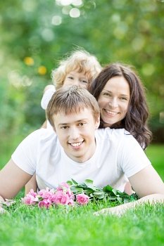Happy family lying on grass against spring green background