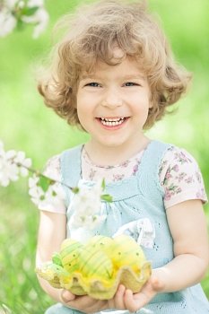 Happy child holding Easter eggs in hands against spring green background