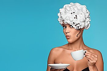 A young lady in a whipped cream on her head with a coffee cup.
