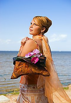 Happy redhead girl on the beach holding floral handbag