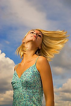 Beautiful blond girl and blue cloudy sky behind her