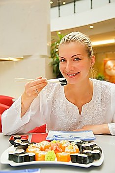 Attractive blond girl eats sushi in a restaurant