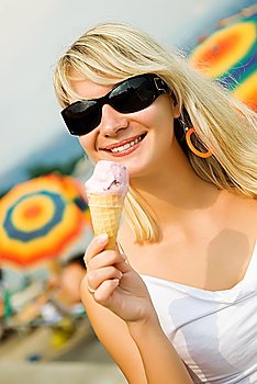 Beautiful young woman eating ice-cream on the beach