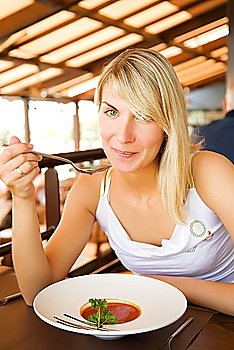 Young woman eating tomato soup in a restaurant