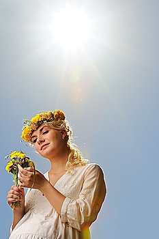Beautiful woman with dandelion flowers over blue sky