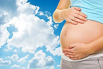 Beautiful pregnant belly over blue cloudy sky