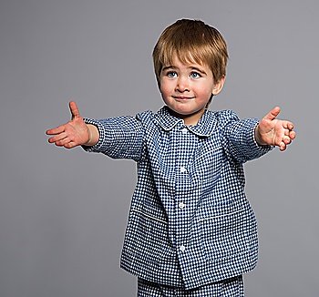 Little boy in blue pyjamas with arms wide open