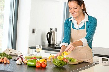 Happy woman making salad kitchen vegetables cooking food