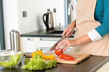 Cook woman cutting tomato vegetables preparing kitchen knife salad
