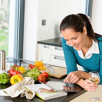 Smiling woman searching recipe tablet kitchen cooking food vegetables