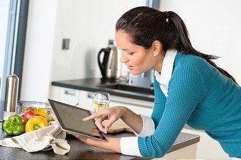 Young woman reading recipe tablet searching kitchen preparing vegetables