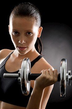 Sporty young woman holding adjustable dumbbell on black background