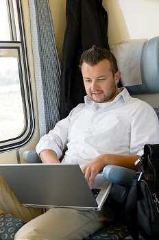 Man sitting in train using laptop computer commuting from work