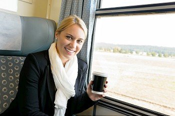 Woman smiling sitting in train holding coffee commuter travel confident