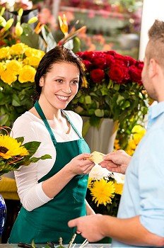 Smiling florist man customer buying flowers credit card shop