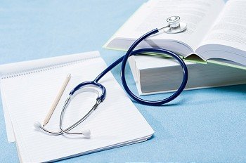 Medical research stethoscope lying over doctor books on blue background