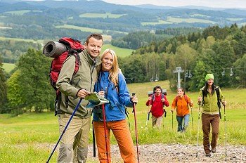 Smiling couple posing with hiking sticks and map on track