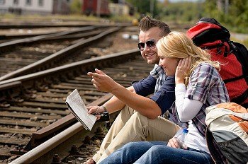 Man pointing direction with map on railroad woman happy couple