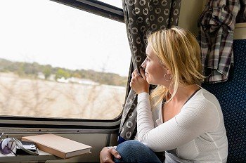 Woman train traveling looking out the window smiling vacation commuter