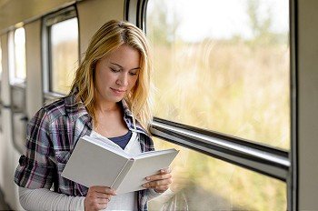 Woman reading a book by train window traveling vacation commuter