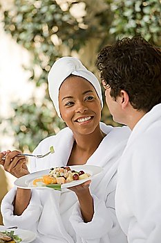 Couple in bathrobes, eating at health spa