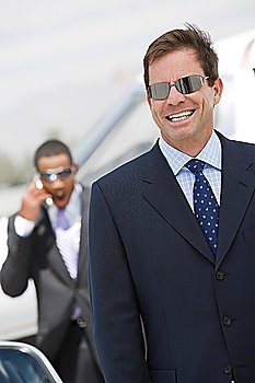 Mid-adult businessman in sunglasses smiling.