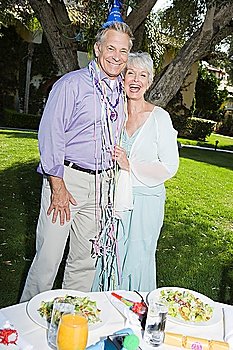 Senior couple embracing and smiling while birthday party in garden