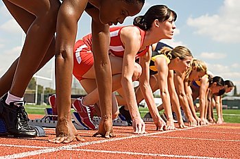 Group of female track athletes on starting blocks