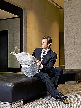 Businessman reading newspaper in lobby
