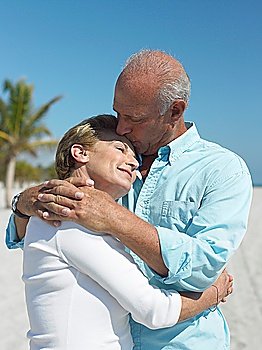 Embracing senior couple kissing on tropical beach