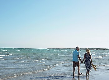 Senior couple walking on beach back view