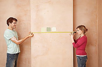 Couple Measuring Wall Before Painting
