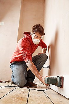 Man Sanding Baseboard Before Painting