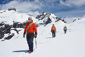 Three hikers joined by safety line in snowy mountains