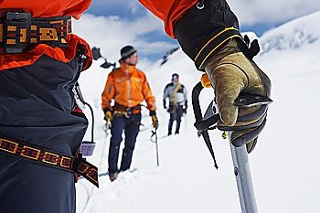 Hikers using walking sticks in snowy mountains mid section on front man
