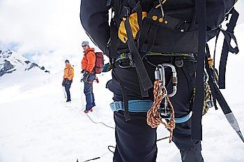 Hiker´s back with backpack and safety rope in snowy mountains with two friends ahead back view