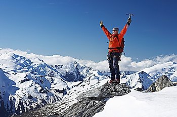 Mountain climber with arms raised on top of mountain peak