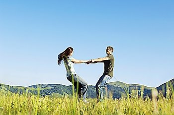 Young couple dancing in mountain field, side view, ground view
