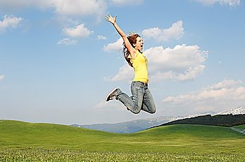 Woman jumping for joy in mountain meadow, side view