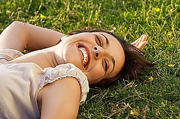 Smiling young woman lying on grass, close up