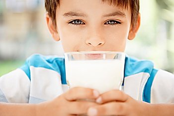 Young boy holding glass of milk portrait close up