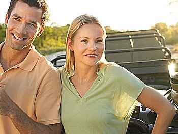 Portrait of couple outdoors standing by jeep smiling