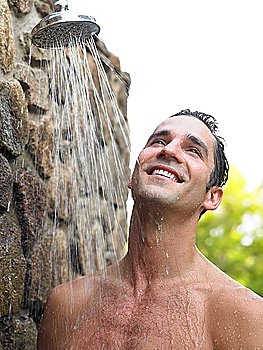 Mid adult man taking shower smiling outdoors