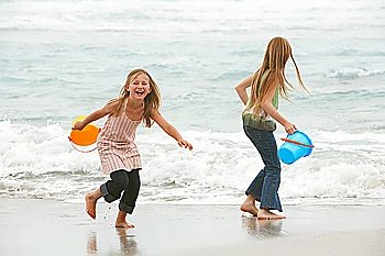 Two girls (7-9 10-12) holding buckets playing on beach