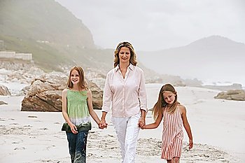 Mother with two daughters (7-9 10-12) walking on beach