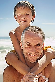 Father carrying son (5-6) on shoulders on beach portrait