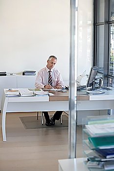 Businessman sitting at desk in office working.