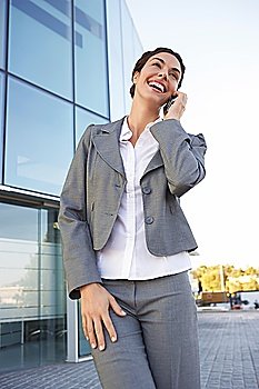 Businesswoman talking on mobile phone in front of office building