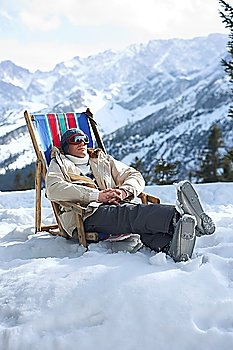 Man sitting on deckchair in snowy mountains